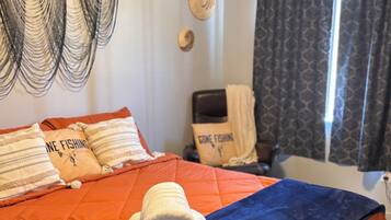 Une chambre d’hôtel avec un lit, des oreillers, une chaise, une fenêtre et des rideaux.