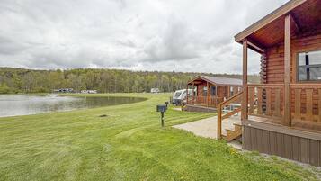 Un chalet au bord du lac, doté d’une terrasse, d’une table de pique-nique et offrant une vue sur le lac et la forêt.