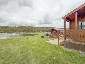 Un chalet au bord du lac, doté d’une terrasse, d’une table de pique-nique et offrant une vue sur le lac et la forêt.