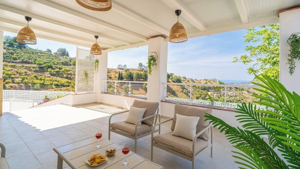 Une terrasse avec une table, des chaises et une vue sur un paysage vallonné.