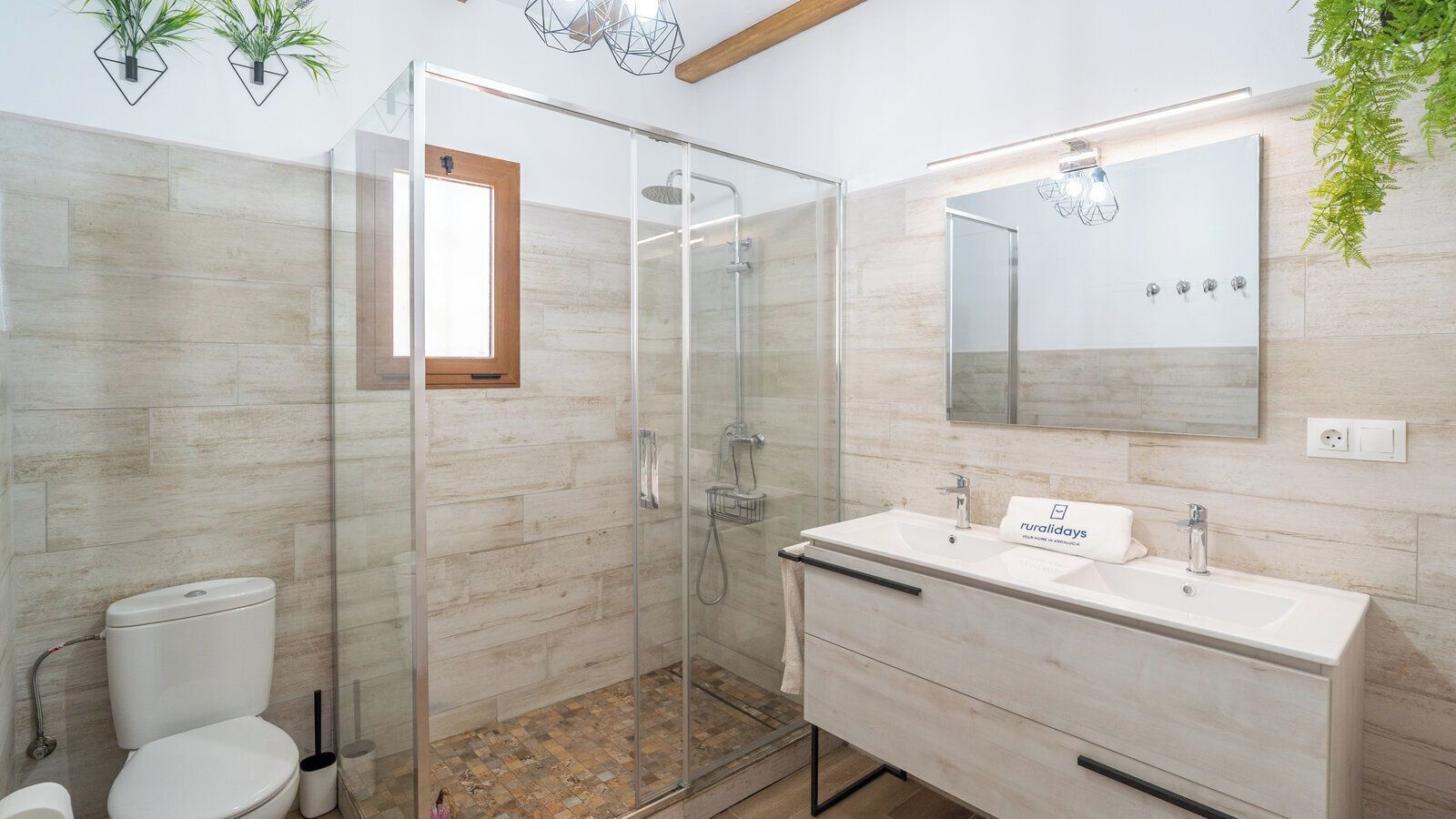 A modern bathroom with a glass shower enclosure, a white sink with a mirror, and a toilet.