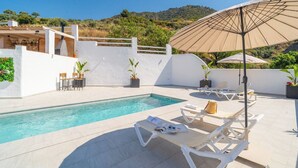 Un espace aménagé au bord de la piscine, avec des chaises longues, une piscine et des plantes en pot.
