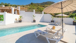 Ein Poolbereich mit Liegestühlen, einem Pool und Topfpflanzen.