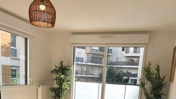 Une chambre à coucher comprenant un lit, une table de chevet, un radiateur, une fenêtre et un luminaire suspendu.