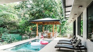 Une piscine dotée de chaises longues, d’un belvédère et offrant une vue sur une végétation luxuriante.