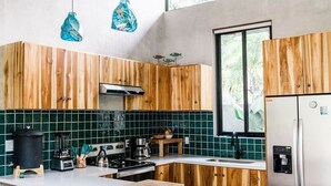 Une cuisine moderne avec des meubles en bois, un réfrigérateur en acier inoxydable et une grande fenêtre.