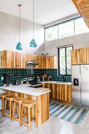 Eine moderne Küche mit Holzschränken, einem Edelstahlkühlschrank und einem großen Fenster.