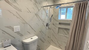 Une salle de bain avec des toilettes, une douche et une fenêtre.