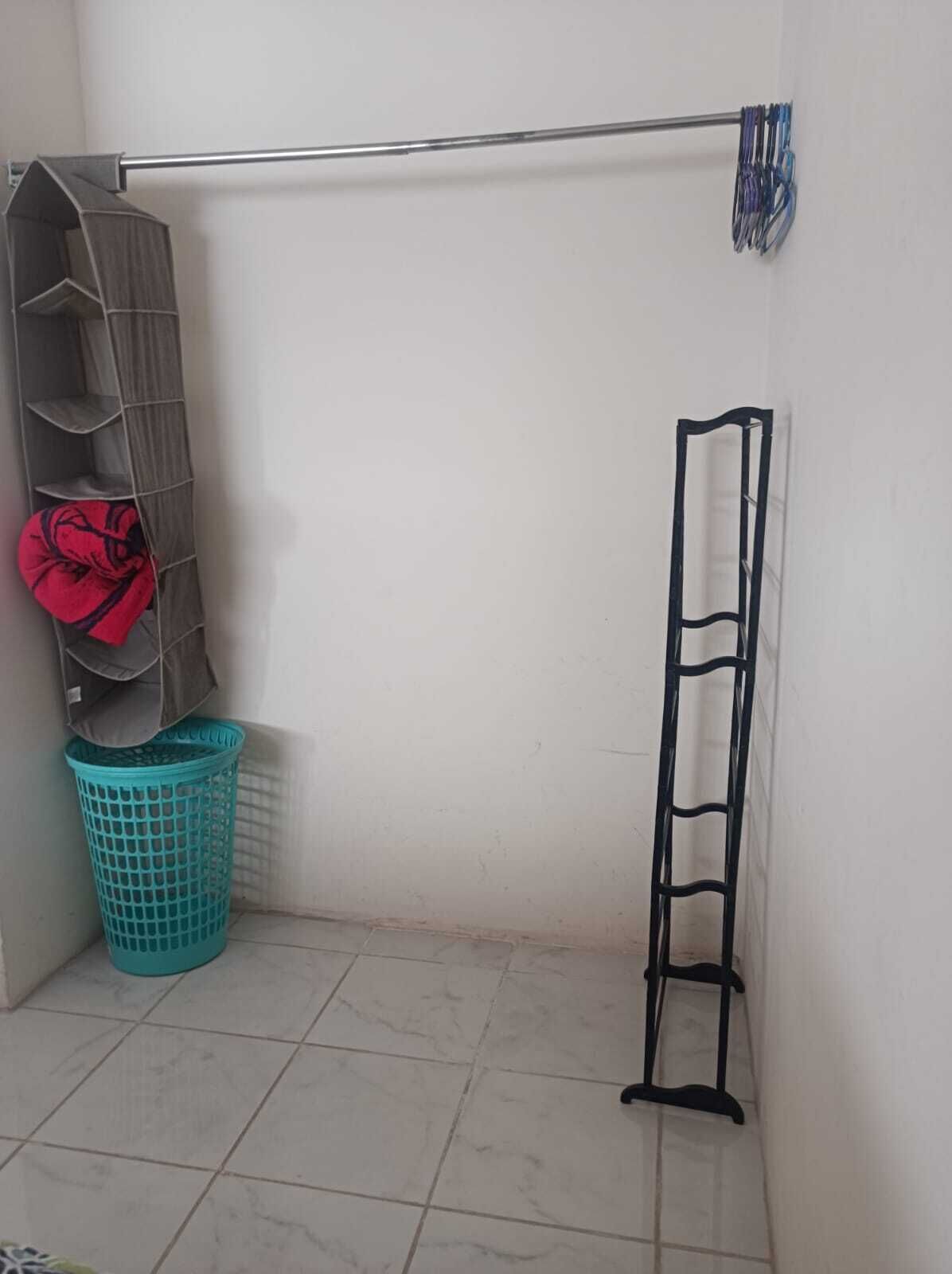 A corner with a metal rack, a grey shelf, and a blue basket.
