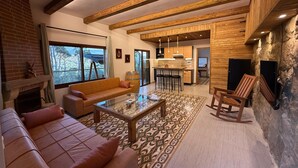 A cozy living area with a fireplace, sofa, coffee table, and a view of the outdoors.