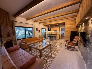Un espacio de sala acogedor con chimenea, sofá, mesa de centro y vistas al exterior.
