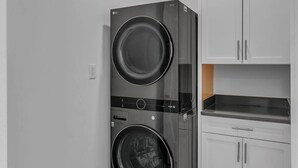 A compact laundry room with a front-loading washer and dryer, white cabinets, and a tiled floor. - Comfort, Space & Convenience – Beautiful 3-Bedroom (Hendersonville)
