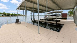 A covered dock with a chair, a ladder, and a boat. - It's A Shore Thing - Boat Slips and Hot Tub (Osage Beach)