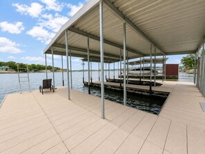 A covered dock with a chair, a ladder, and a boat. - It's A Shore Thing - Boat Slips and Hot Tub (Osage Beach)