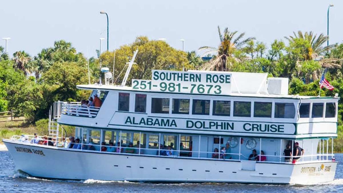 A white boat with 'Southern Rose' and 'Alabama Dolphin Cruise' written on the side, a phone number, and a flag.