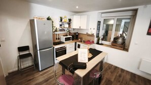 A compact kitchen with a refrigerator, microwave, and a small dining area with stools. - House les acacias - 6 people (Mauléon)
