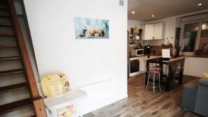 A modern kitchen with white cabinets, a dining area with a table and chairs, and a staircase. - House les acacias - 6 people (Mauléon)
