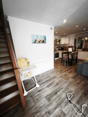 Eine moderne Küche mit weißen Schränken, einem Essbereich mit Tisch und Stühlen sowie einer Treppe.