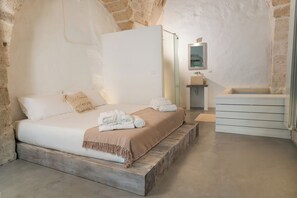 Une chambre à coucher comprenant un lit, une table de chevet, un miroir et une petite salle de bain.