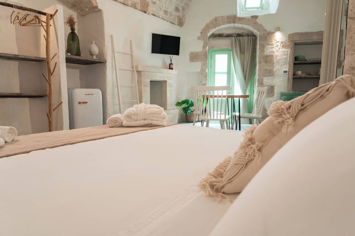 Un dormitorio con cama, televisor, chimenea y pared de piedra.