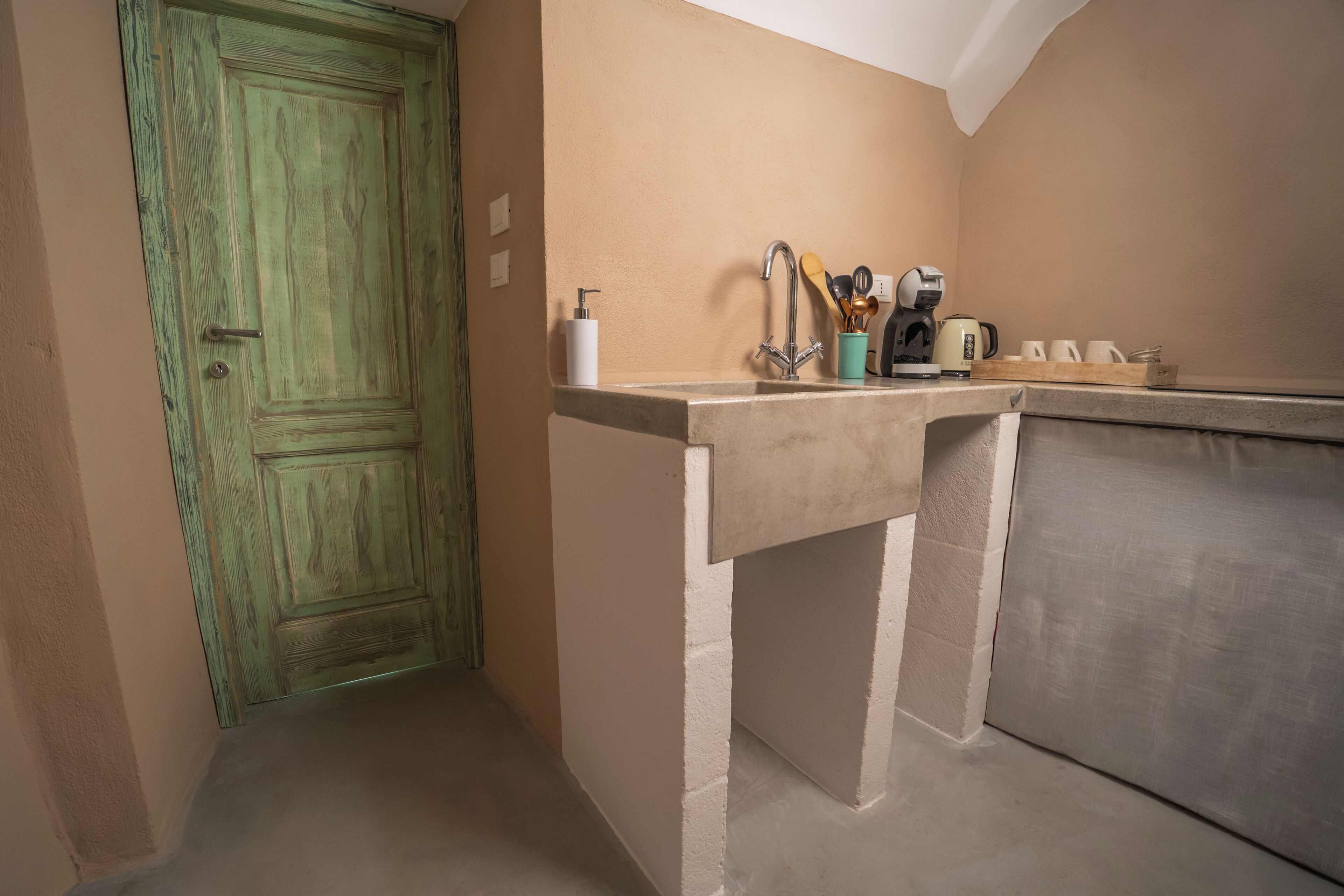 Una cucina piccola con una porta verde, un lavandino e un briccoel.