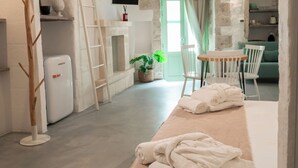 Una habitación rústica con paredes de piedra, chimenea, escalera de madera, mesa con sillas y televisor montado en la pared.