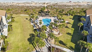 Et resort med swimmingpool, palmer og udsigt til stranden.