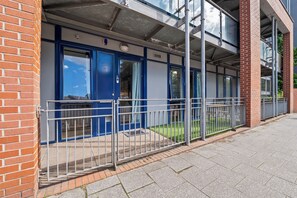 A building with a blue door, a metal fence, and a brick wall. - Welcome to "your space" with Private Patio (Birmingham)