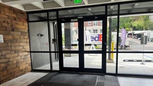 A hotel entrance with a glass door, a wooden wall, and a tiled floor. - 8th Floor Studio Rental with High Ceilings! (Spokane)