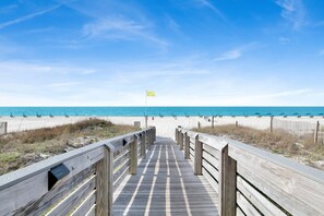 A wooden boardwalk leading to a beach with a flag. - Beachfront 2BR @ Admiral Quarters • Sleeps 8 • Stunning Views (Orange Beach)
