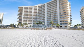 A beachfront hotel with multiple balconies, palm trees, and a sandy beach. - Beachfront 2BR @ Admiral Quarters • Sleeps 8 • Stunning Views (Orange Beach)