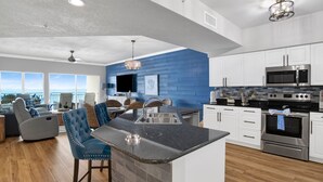 A modern kitchen with a large island, stainless steel appliances, and a view to the outside. - Beachfront 2BR @ Admiral Quarters • Sleeps 8 • Stunning Views (Orange Beach)