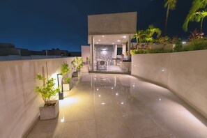 A modern outdoor patio area with a dining table and chairs, surrounded by potted plants and a curved wall. - Chic studio in the best location. Swimming pool and gym. (Playa del Carmen)
