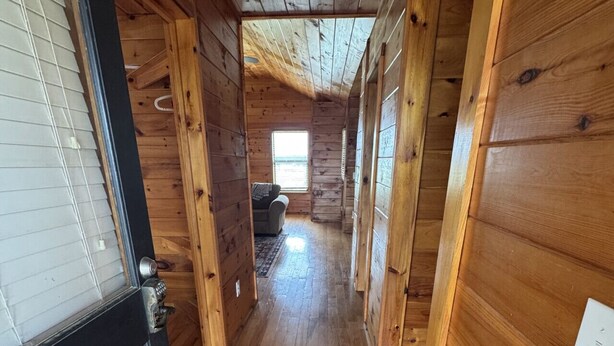 Un interno in legno con un corridoio che conduce a una stanza con una finestra.