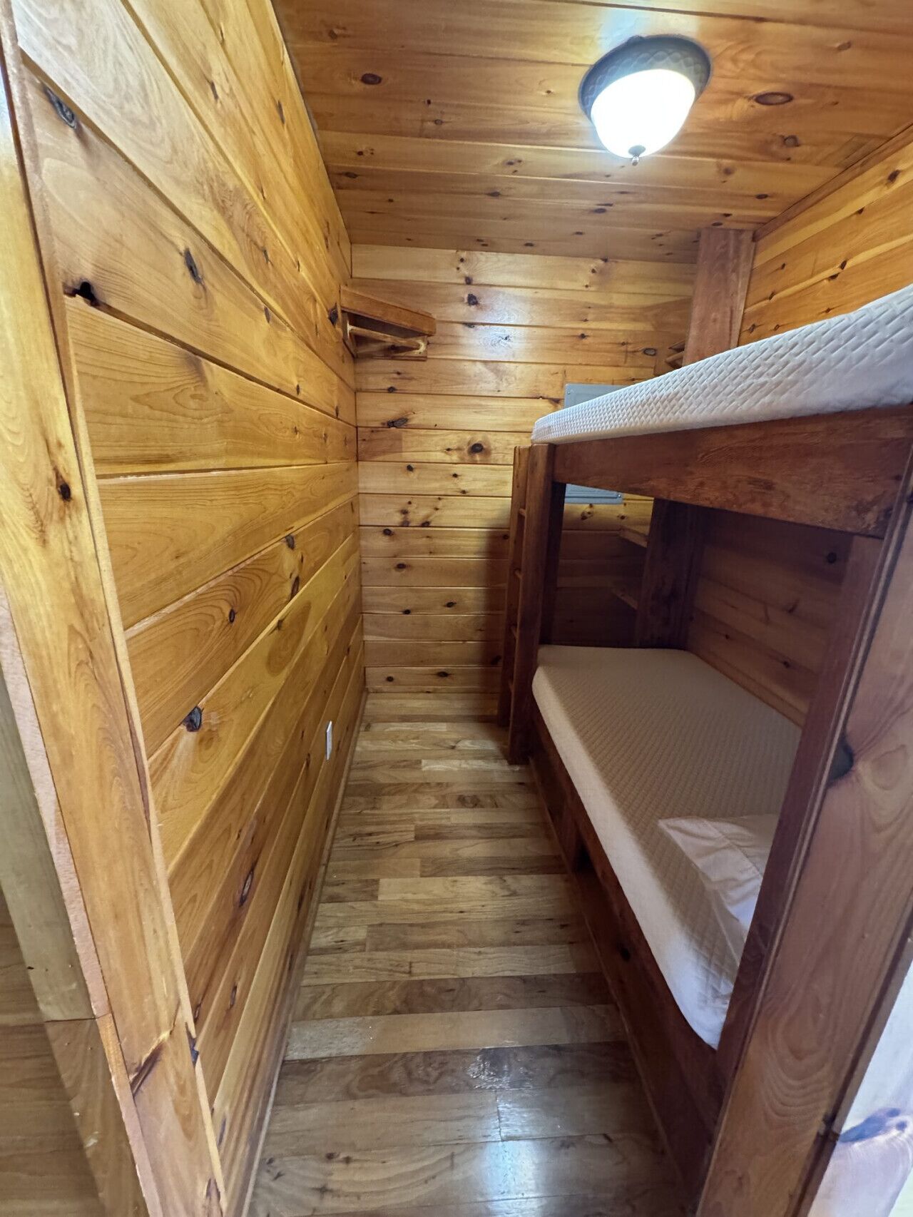 Une petite pièce en bois, avec des lits superposés et un plafond en pente.
