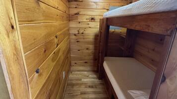 Une petite pièce en bois, avec des lits superposés et un plafond en pente.
