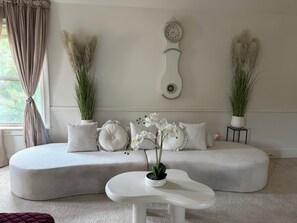 Ein modernes Wohnzimmer mit einer Couch, einem runden Couchtisch und Zimmerpflanzen.