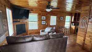 En inredning med träpanel, en soffa, ett tv-appar, en takfläkt och träskåp.