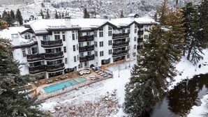 Un hotel de varios pisos con balcones, piscina y vistas a montañas nevadas.