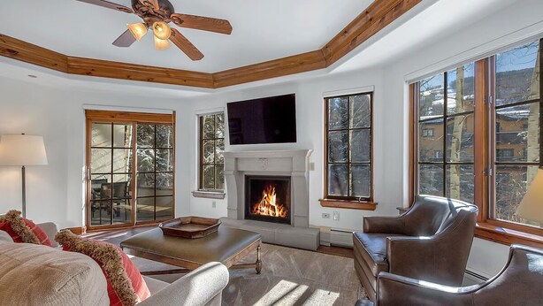 Una sala de estar con chimenea, sillones de cuero, un sofá y un televisor.