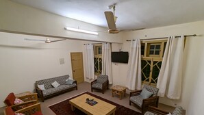 Un salon comprenant un canapé, des fauteuils, une table basse, un téléviseur et un ventilateur de plafond.