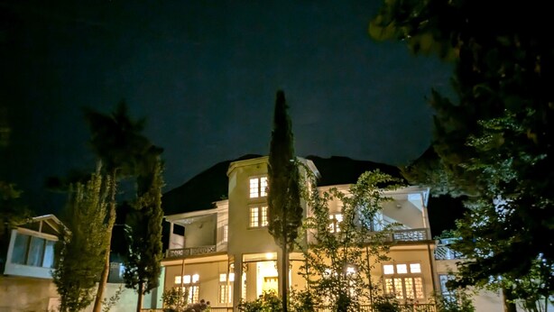 Un immeuble à plusieurs étages, doté de fenêtres illuminées et d’une pelouse bien entretenue.