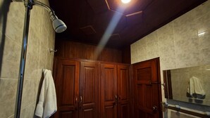 Une salle de bain avec des meubles en bois, un miroir, un lavabo et une douche.