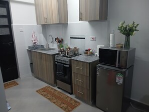 Eine moderne Küche mit Holzschränken, einem Herd, einer Spüle und einem Kühlschrank.