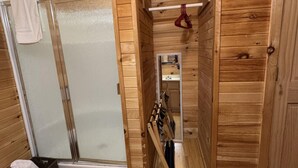 A wooden cabin interior with a shower, a small mirror, and a wooden bench. - Ranch House 6 at Lamb Ranch (Michie)