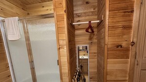 A wooden interior with a shower, a towel rack, and a white bathtub. - Ranch House 6 at Lamb Ranch (Michie)