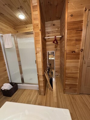 A wooden interior with a shower, a towel rack, and a white bathtub. - Cabin 6 at Lamb Ranch (Michie)
