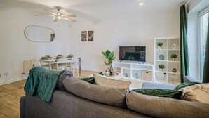 A modern living room with a sofa, a dining table, a TV, and a plant. - Labrador Quay  (Salford)