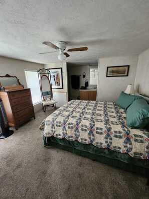 Un dormitorio con cama, cómoda, tocador y ventilador de techo.