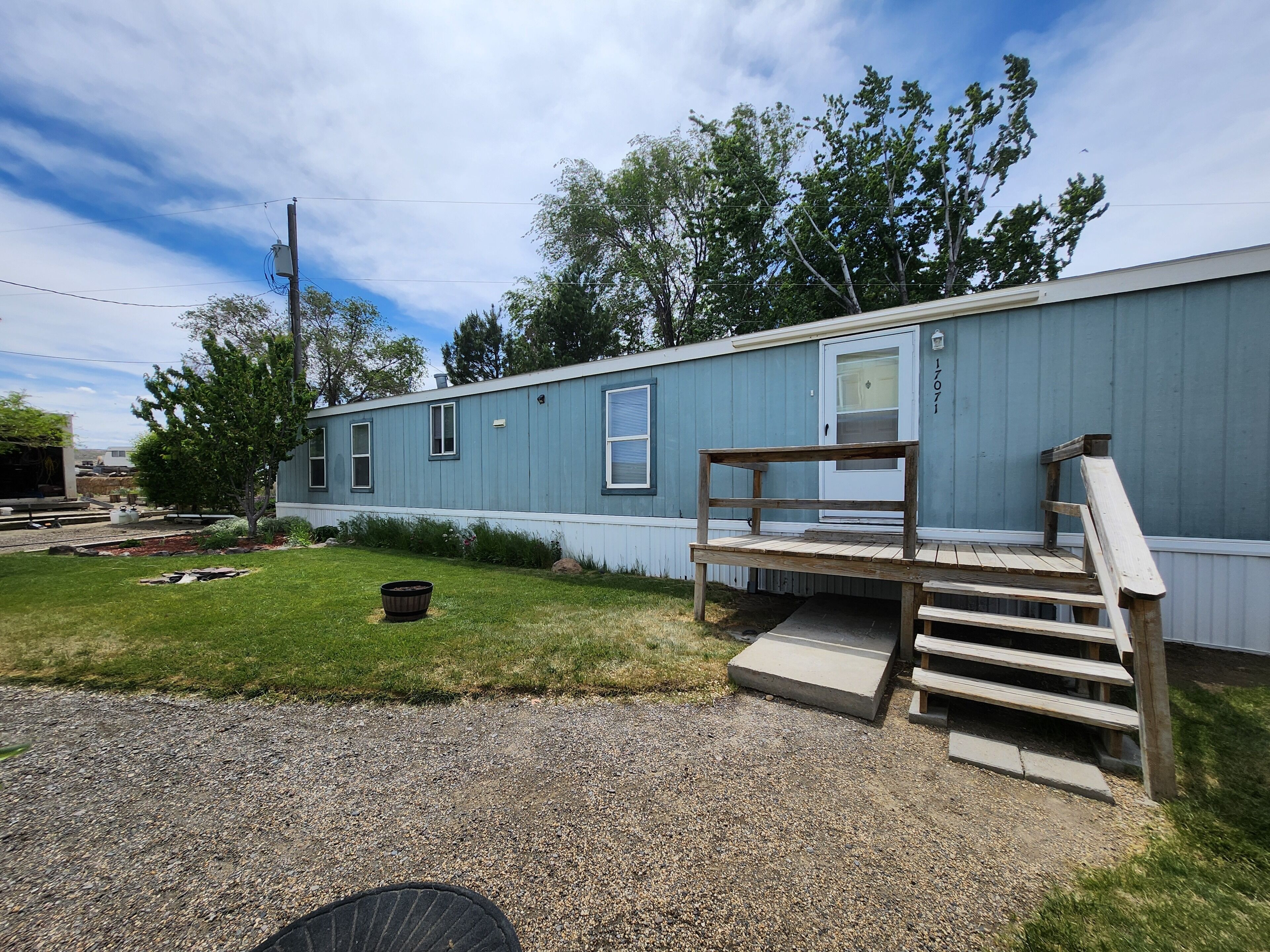 A single-story mobile home with a front porch and a small deck.